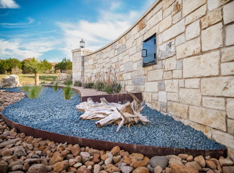 natural rock and driftwood with steel raised beds for gated entrance landscape design in central Texas
