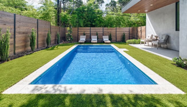 modern backyard landscape design with horizontal fence, spruce trees along fence line, and in-ground pool