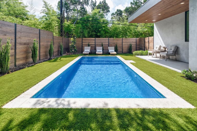 modern backyard landscape design with horizontal fence, spruce trees along fence line, and in-ground pool