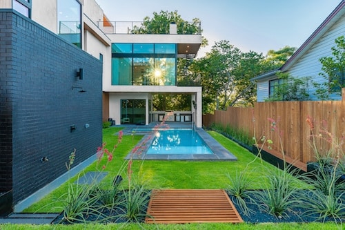 narrow backyard in Austin, Texas with new landscape design, poolside landscaping, an outdoor shower, and a modern aesthetic