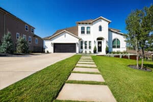 Front yard landscape design with large stone walkway leading up to white two-story house