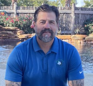 Jason Stubblefield, owner of Best of Texas Landscapes, sitting in front of pool and landscaping in Leander, Texas