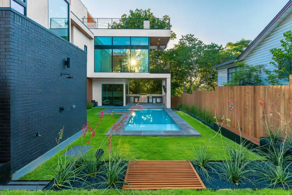 landscape design with plants and raised beds around modern pool and outdoor kitchen