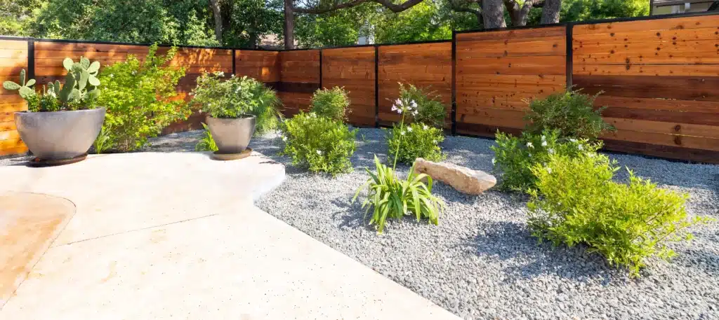 Shoal Creek home backyard xeriscape design with horizontal fence and large planting pots
