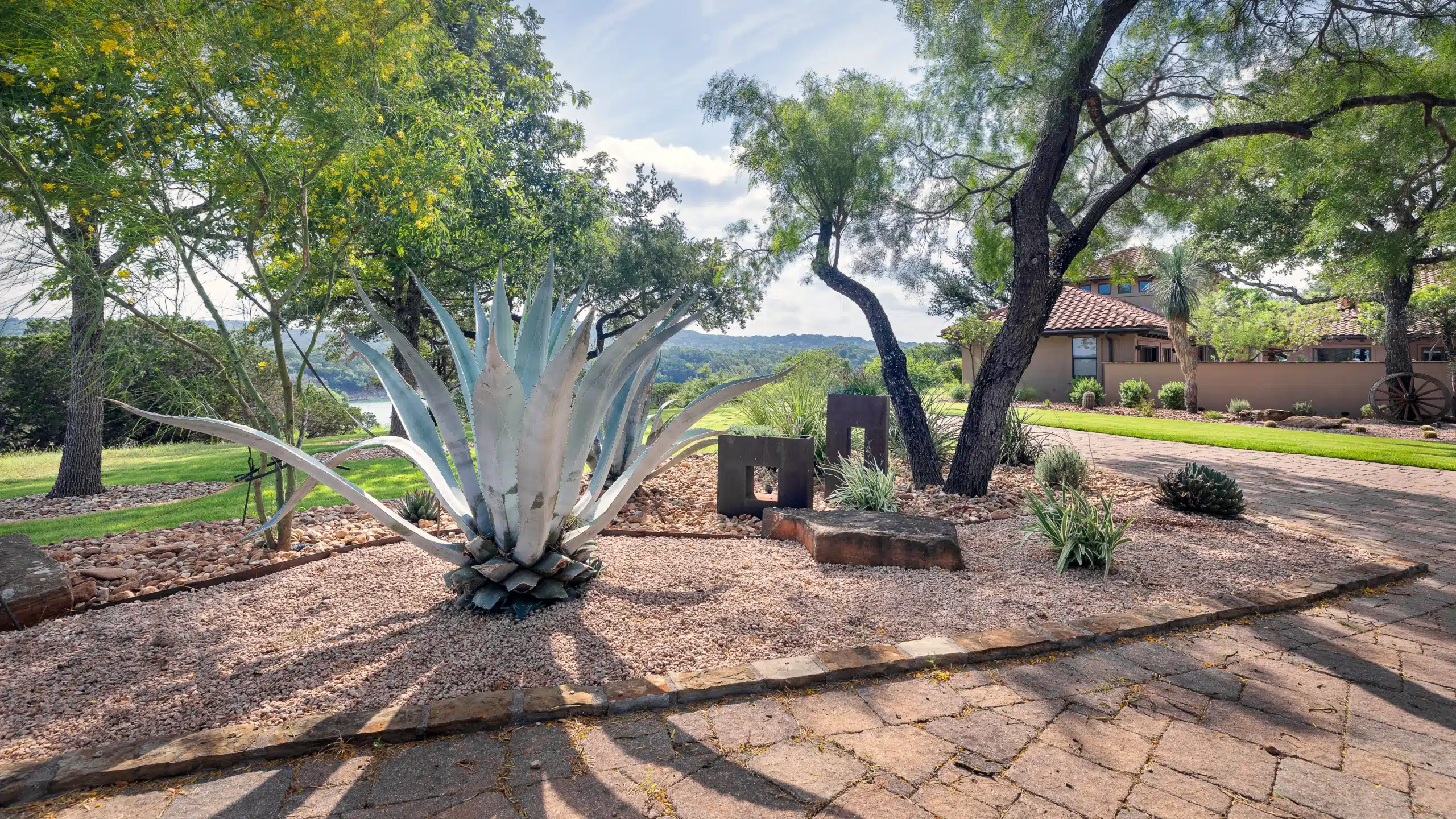 large yucca accented with steel planters and natural stone along driveway of spanish style home