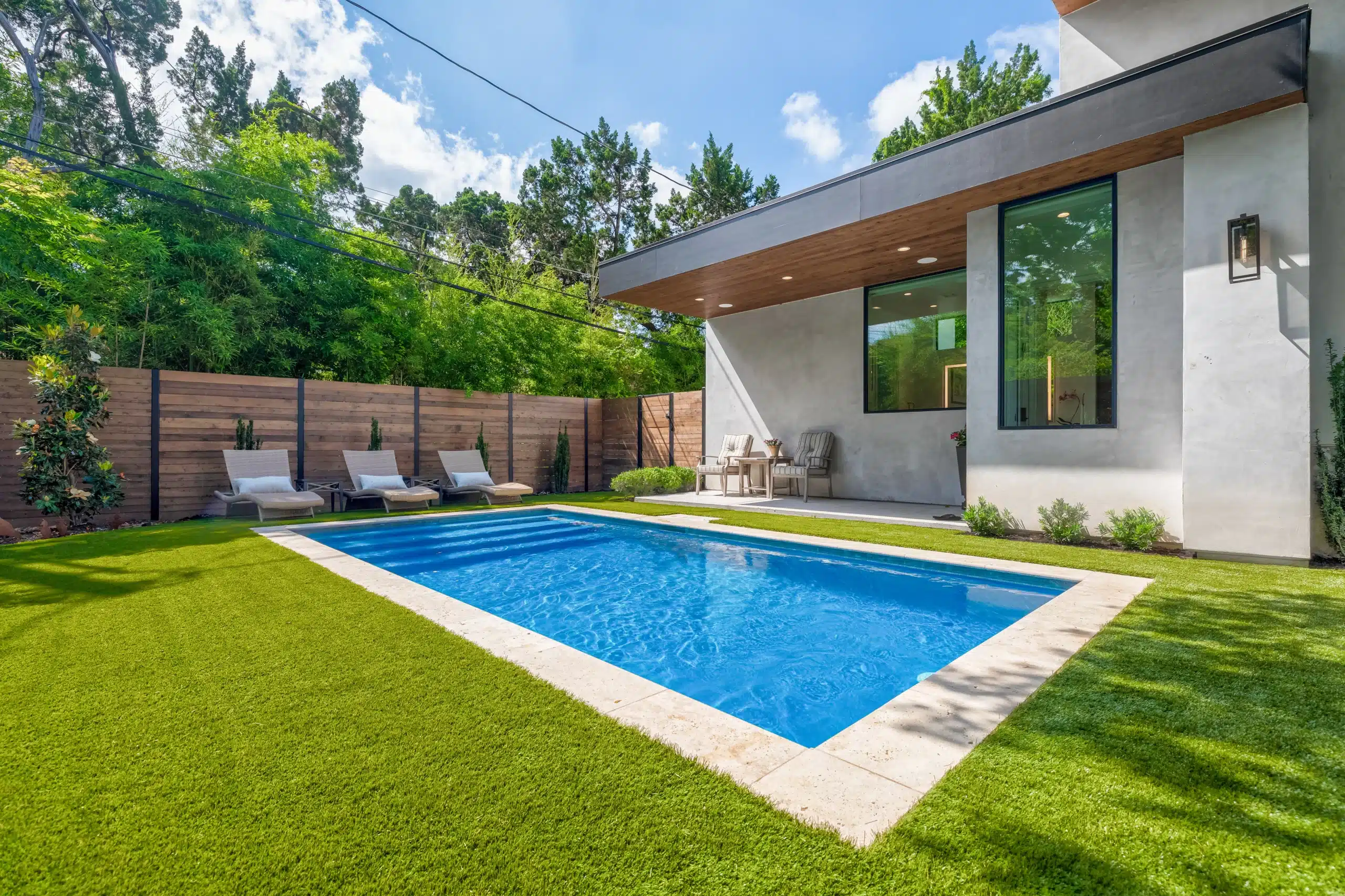 backyard in-ground pool with lounge chairs and horizontal privacy fence
