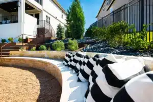 outdoor designs with backyard seating made of natural stone with white and black pillows below tiered raised plant beds