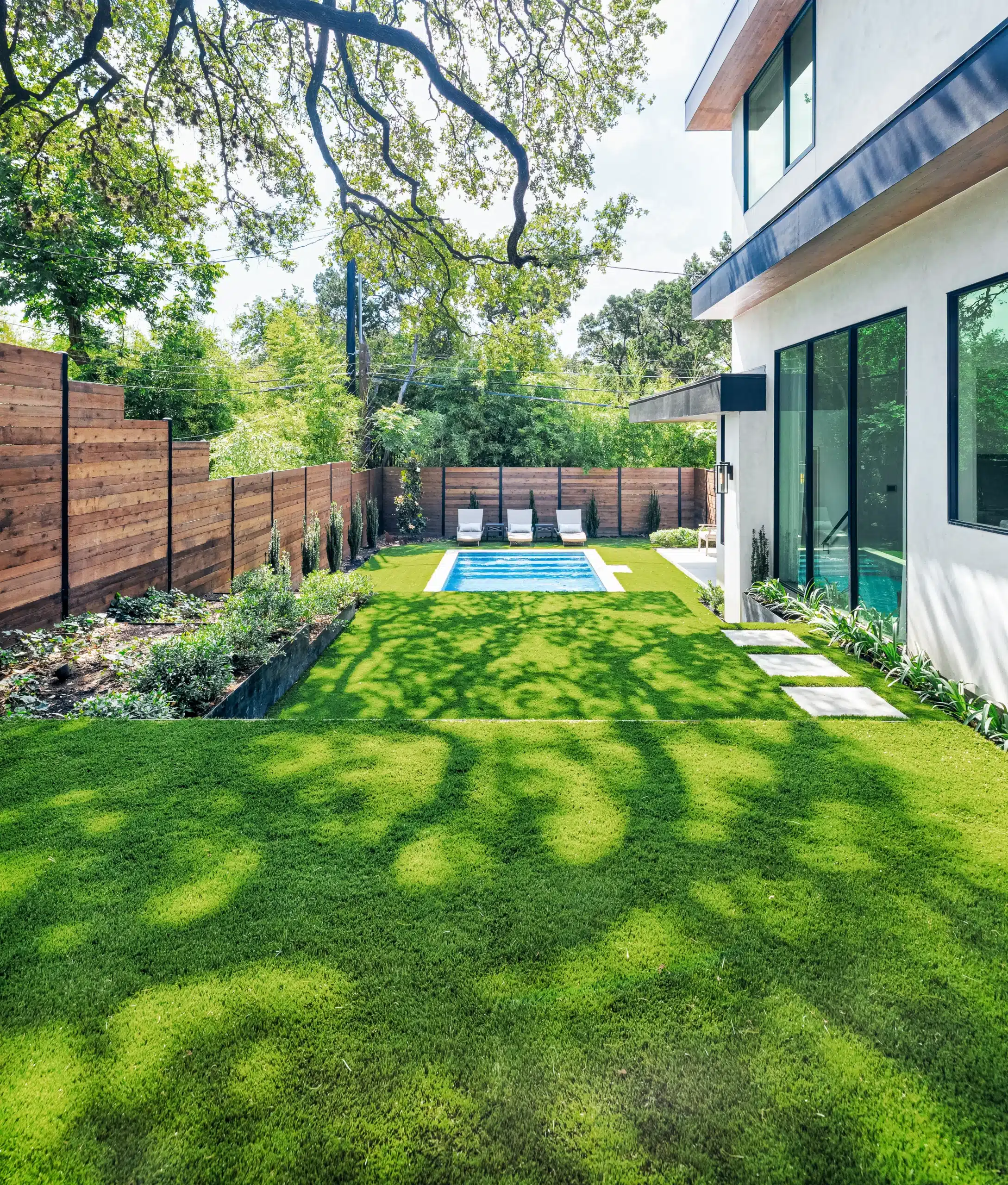 tiered backyard with raised plant beds and walkway going down to rectangular pool