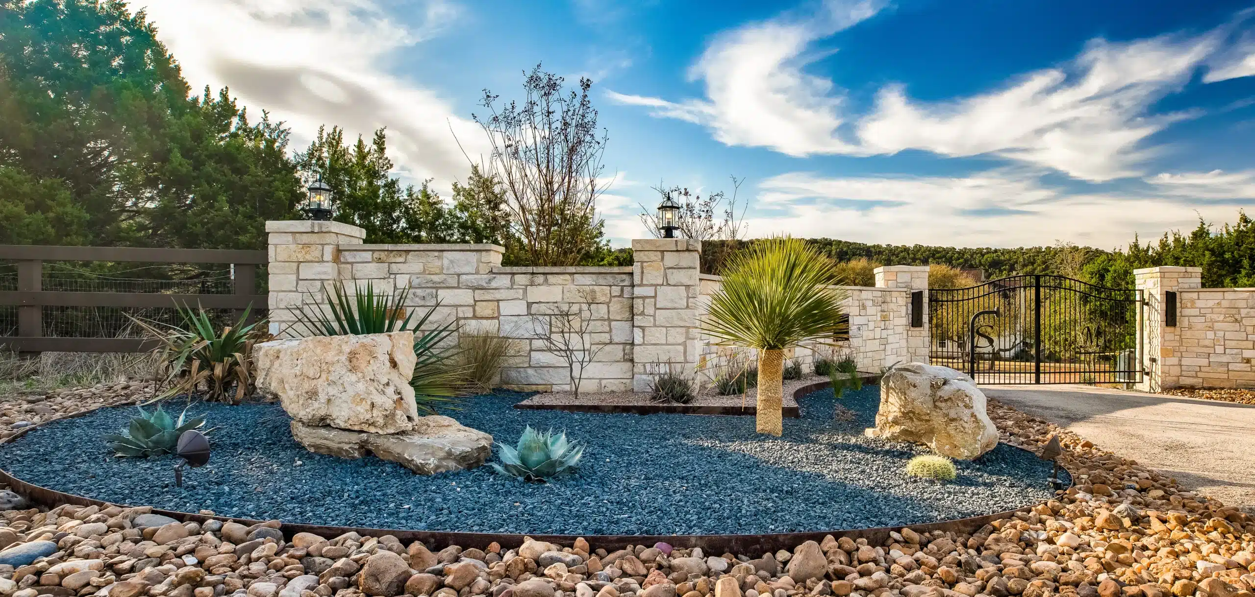 front gated entry of rural home with landscaping of natural rock, steel edging, native plants and outdoor lighting