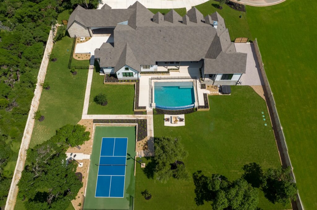 aerial view of backyard landscape design with tennis court, pool, fire pit, seating areas for high end home