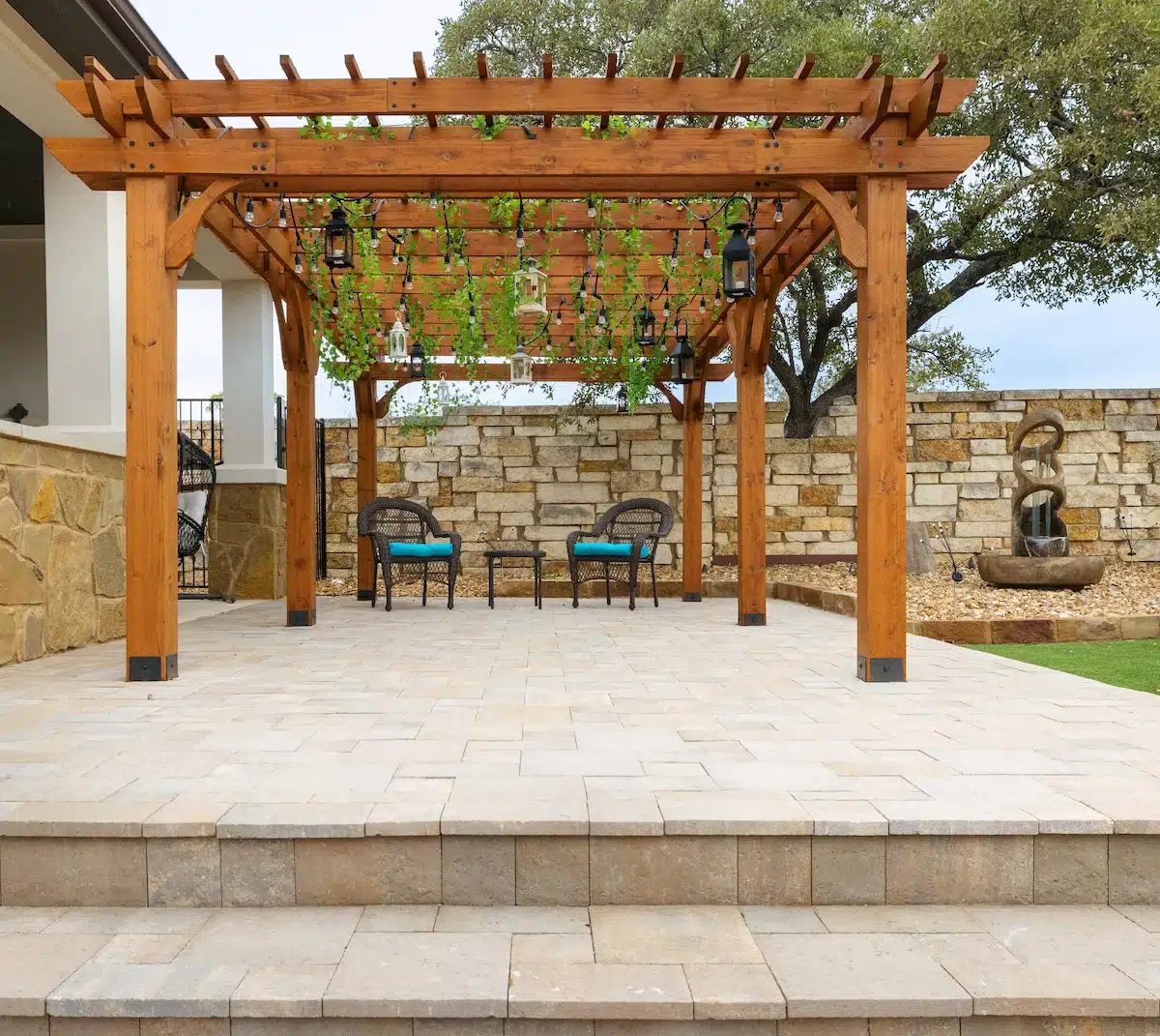 pergola with antique style lanterns and outdoor seating near outdoor sculpture for backyard landscape design in Georgetown, Texas