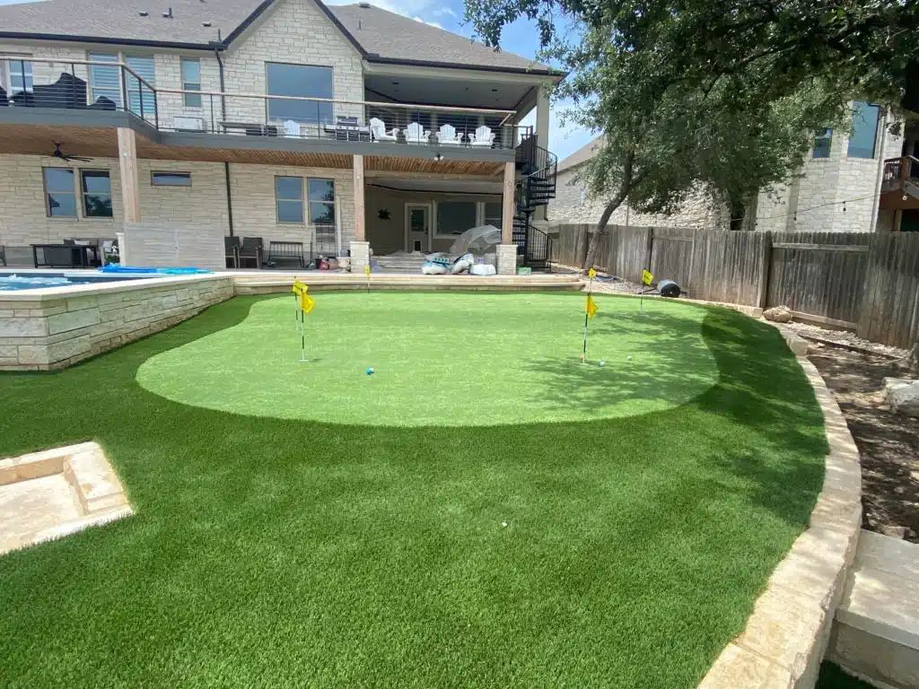 mini golf course in backyard next to in-ground pool behind two story home with multi-level deck