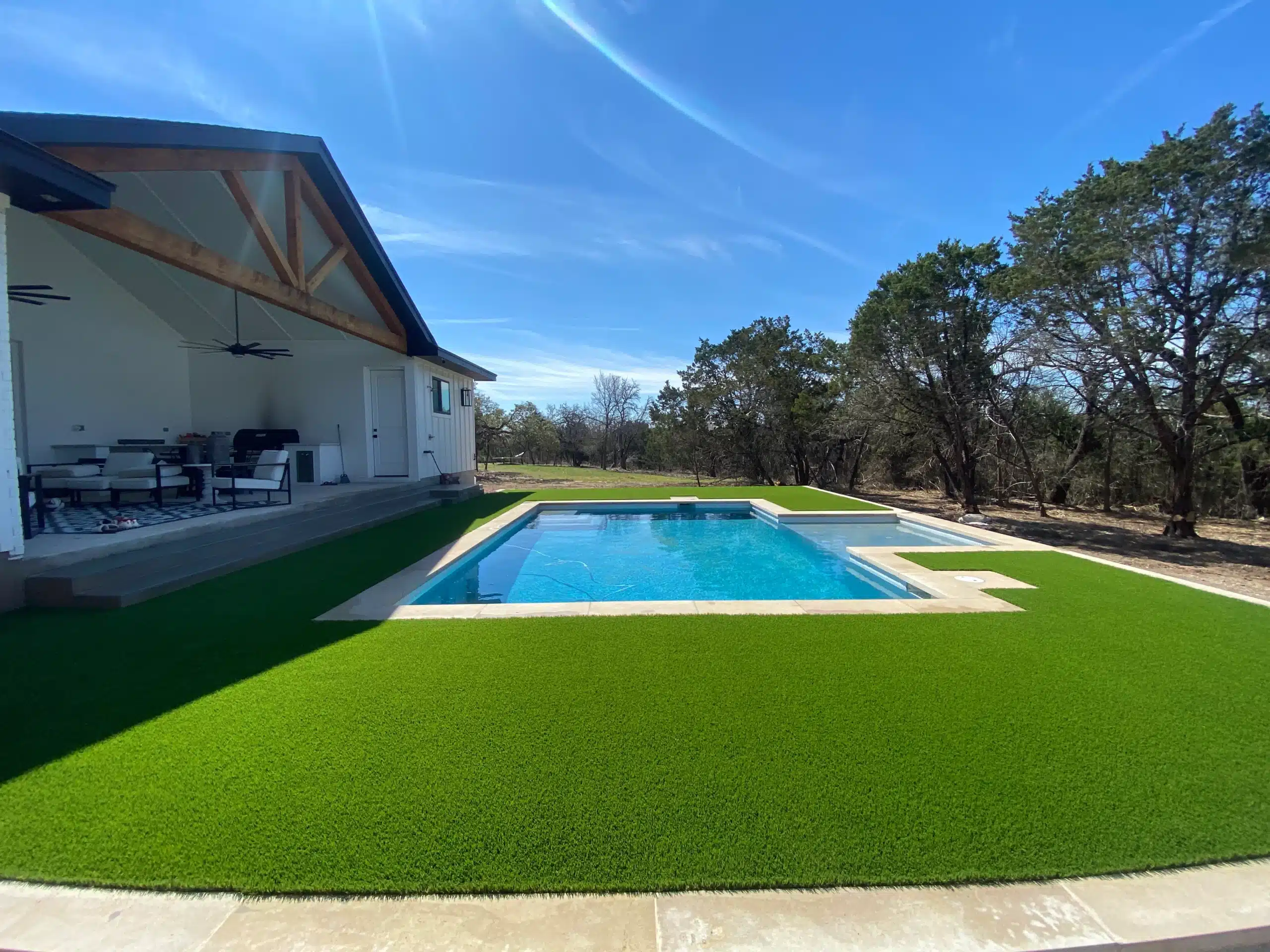 backyard surrounded by trees with raised area for in-ground pool surrounded by turf