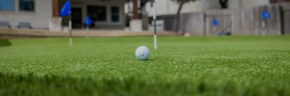 landscape design with closeup of golf ball on putting green on backyard putting green in Cimarron Hills