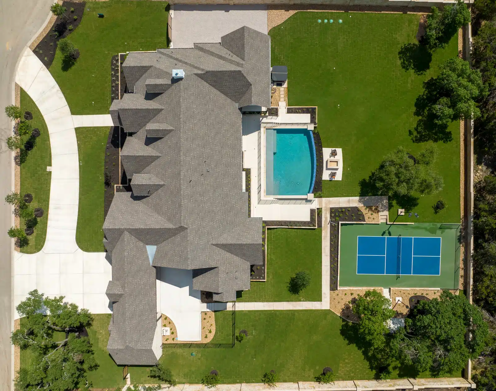 aerial view of backyard rec area with tennis court and pool and landscape design in Georgetown, Texas by Best of Texas Landscapes