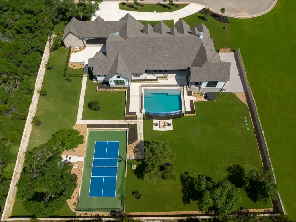 aerial view of backyard tennis court, pool, and landscape design for Georgetown, Texas home by Best of Texas Landscapes