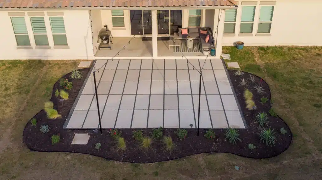 aerial view of backyard patio extension lined with mulch plant bed and two poles holding strands of outdoor lights
