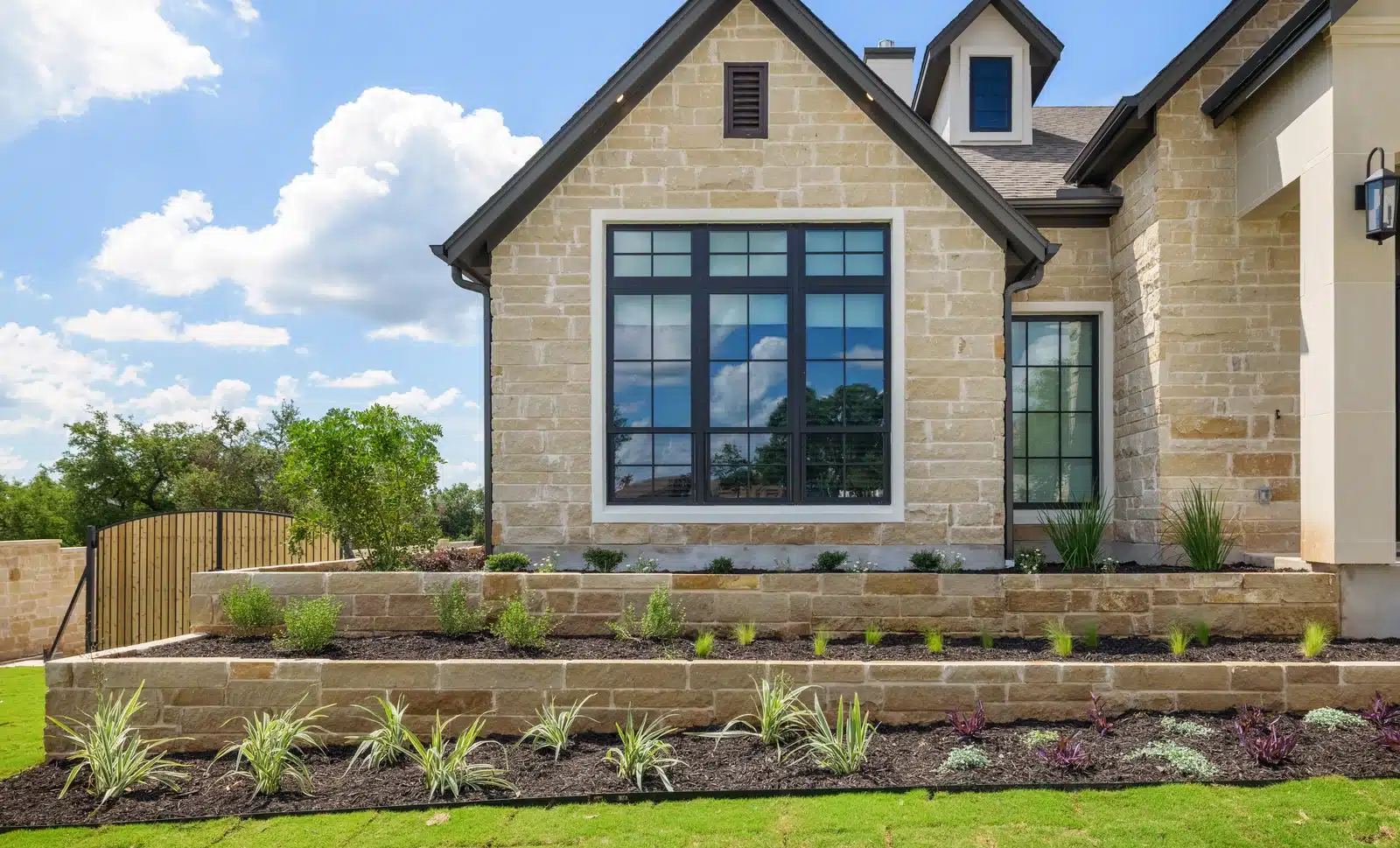 raised stone plant beds with mulch and landscaping plants in front yard by Best of Texas Landscapes